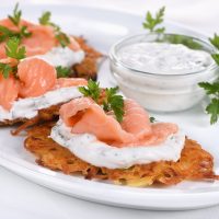 Crispy Potato fritters (a pancake, especially one made with grated potato) with cream cheese sauce with herbs and salmon